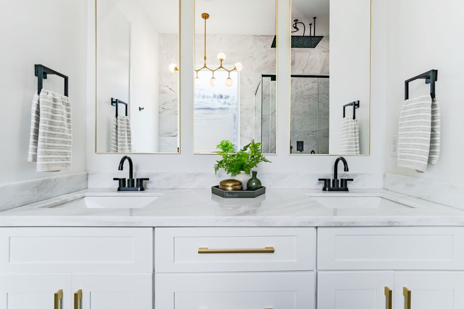 Symmetrie versus asymmetrie: de grote badkamerstijl dilemma - Heldere, elegante badkamerinrichting met dubbele wastafels, spiegels en moderne verlichting in New Orleans. Symmetrie versus asymmetrie: de grote badkamerstijl dilemma - Heldere, elegante badkamerinrichting met dubbele wastafels, spiegels en moderne verlichting in New Orleans.